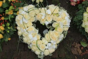 Heart Shaped sympathy or funeral flowers near a tree at a cemetery