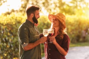 Happy friends having fun drinking wine at winery vineyard - Friendship concept with young people enjoying harvest time together